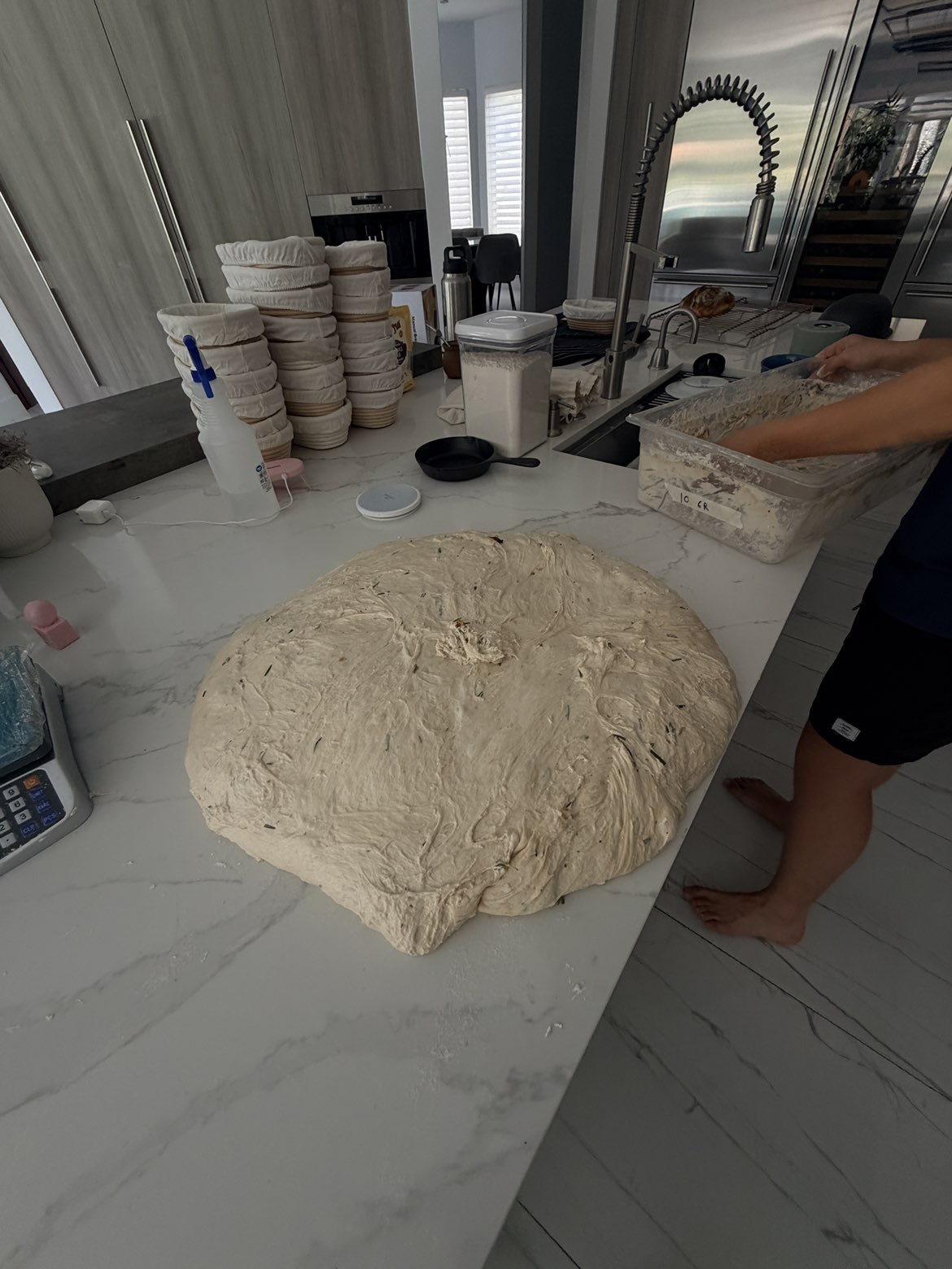 A large batch of sourdough dough being prepared on a kitchen island